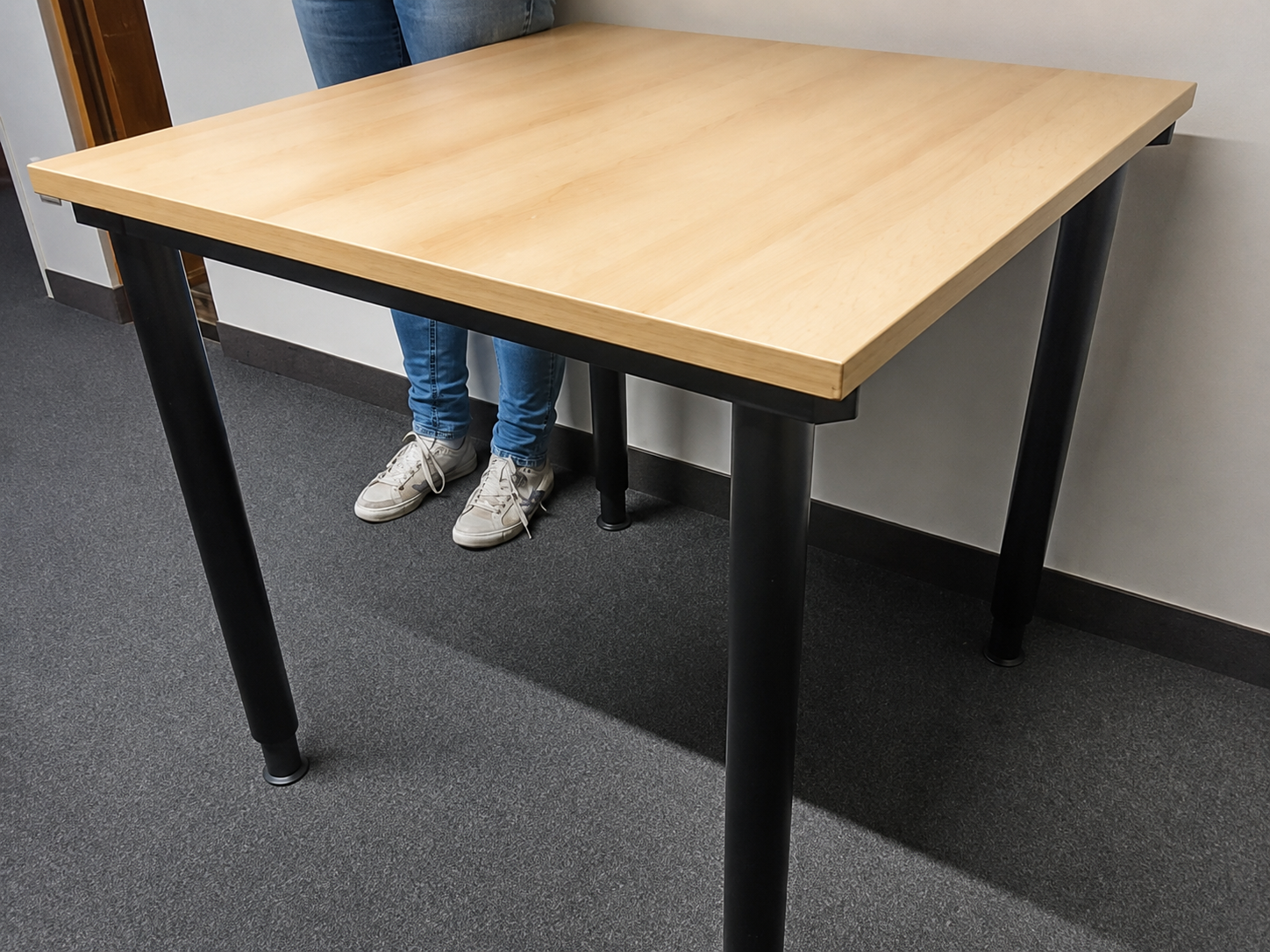 Holztisch mit schwarzen Beinen in einem Raum.